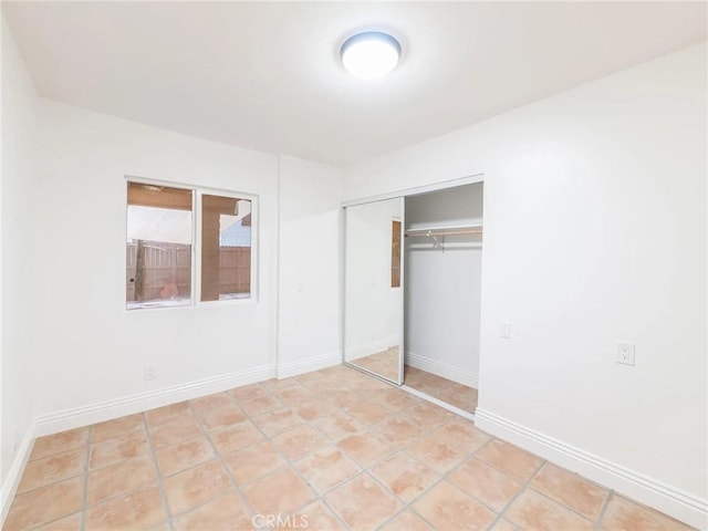 unfurnished bedroom with a closet, tile patterned flooring, and baseboards