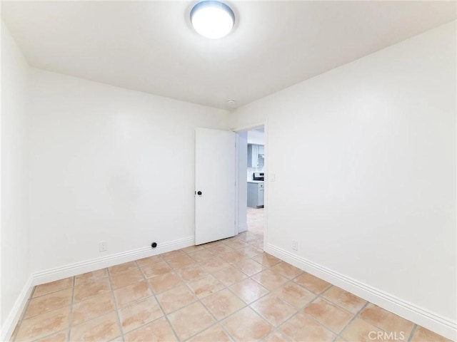 spare room featuring baseboards and light tile patterned floors