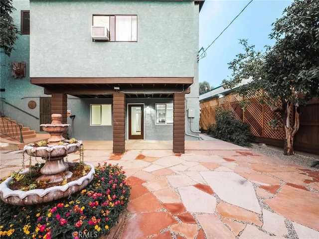 rear view of house featuring stucco siding, fence, and a patio