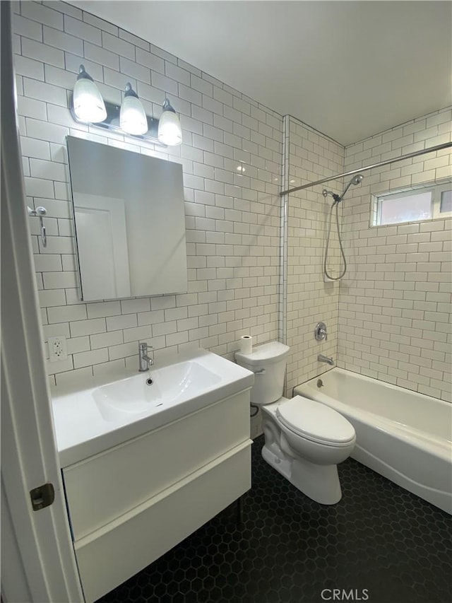 bathroom featuring tasteful backsplash, toilet, vanity, shower / bathtub combination, and tile walls