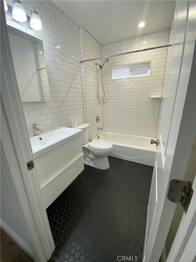 bathroom featuring tile patterned flooring, toilet, shower / bath combination, vanity, and tile walls