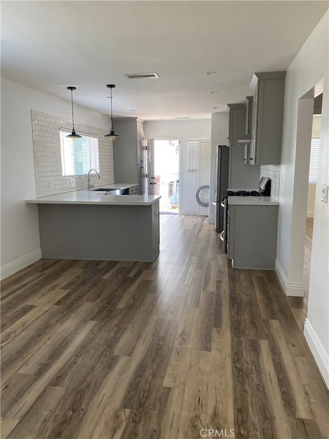 kitchen with a peninsula, freestanding refrigerator, visible vents, and gray cabinetry