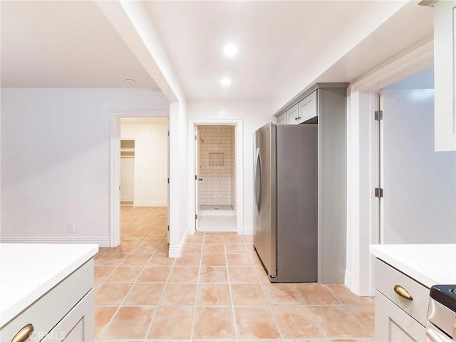 kitchen featuring freestanding refrigerator, gray cabinets, light countertops, and light tile patterned floors