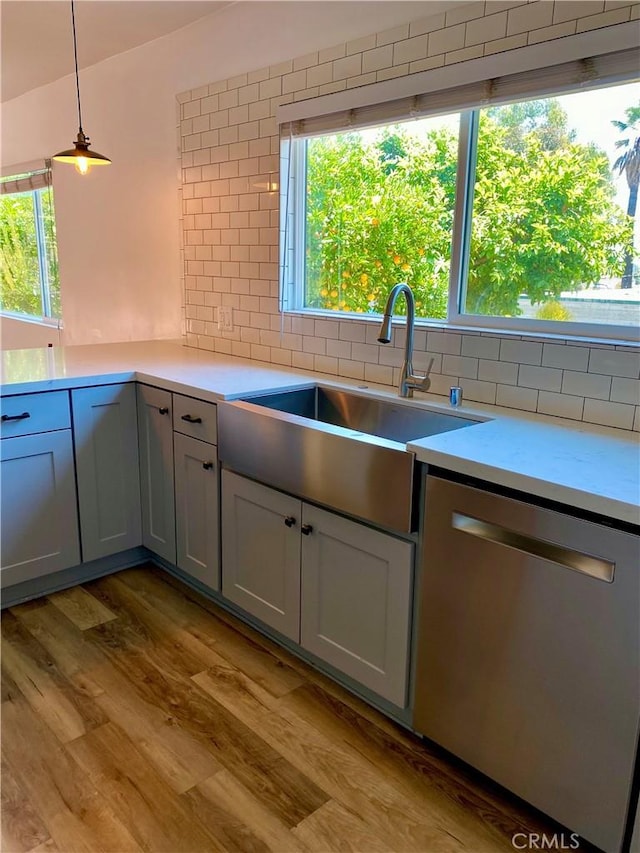 kitchen with dishwasher, light countertops, hanging light fixtures, and a sink