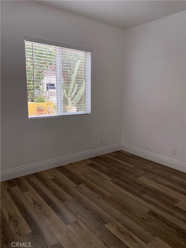 empty room with dark wood-style floors and baseboards