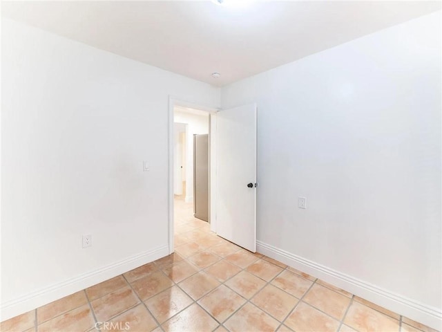 unfurnished room featuring light tile patterned floors and baseboards