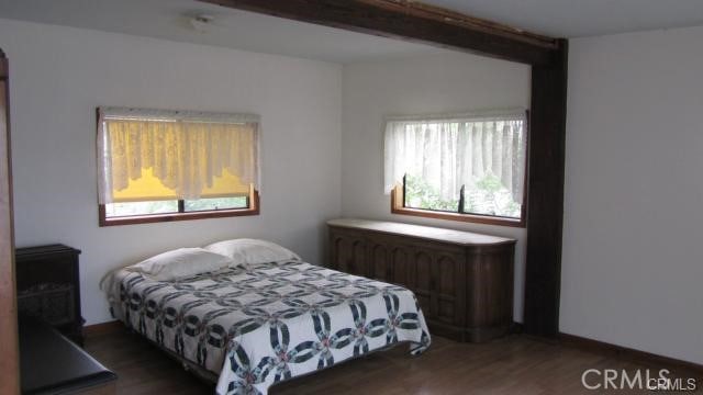 bedroom with radiator, dark wood-style flooring, and beamed ceiling