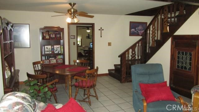 dining space featuring light tile patterned floors, ceiling fan, and stairway