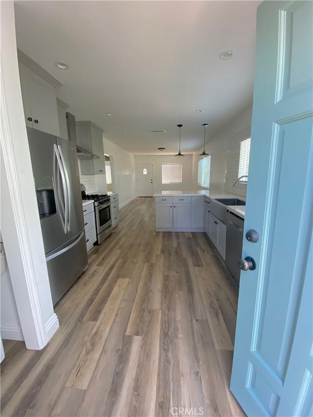 kitchen with pendant lighting, stainless steel appliances, light countertops, and gray cabinetry