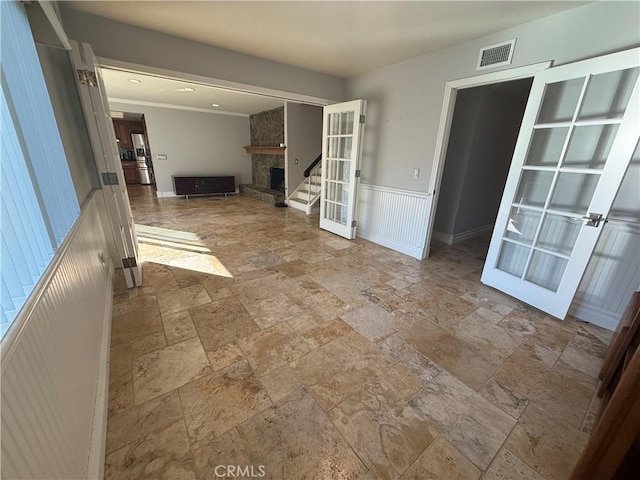 7122 Bluesails Dr, Huntington Beach, CA 92647 - unfurnished living room with french doors, visible vents, a stone fireplace, and wainscoting