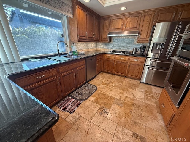 7122 Bluesails Dr, Huntington Beach, CA 92647 - kitchen with stainless steel appliances, under cabinet range hood, stone tile floors, tasteful backsplash, and brown cabinets