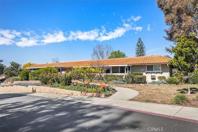 ranch-style house featuring a tile roof and stucco siding