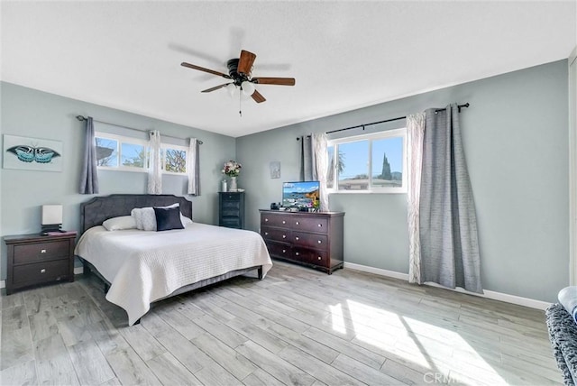 bedroom with light wood finished floors, multiple windows, and baseboards