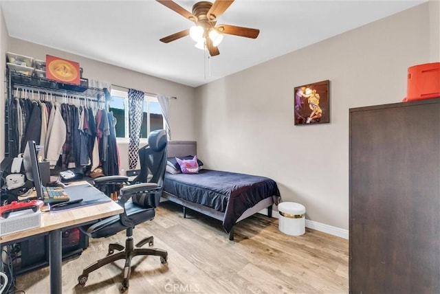 bedroom featuring ceiling fan, light wood-style flooring, and baseboards