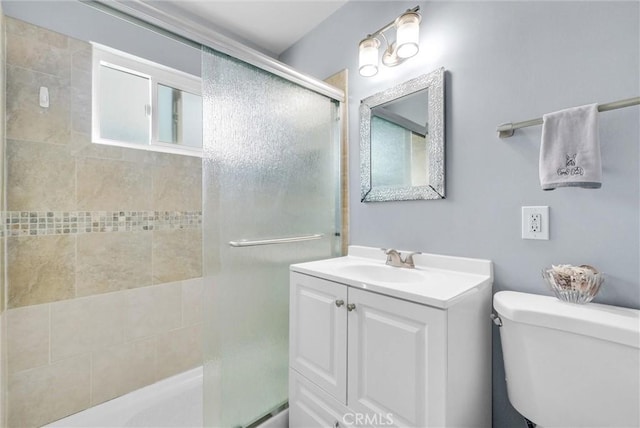 full bathroom featuring a tile shower, vanity, and toilet