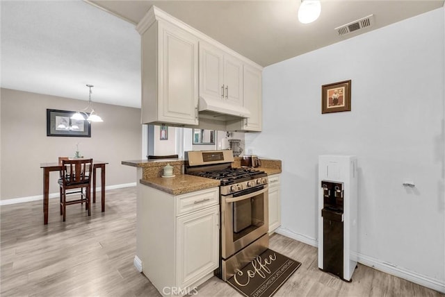 kitchen featuring under cabinet range hood, visible vents, white cabinets, hanging light fixtures, and stainless steel range with gas cooktop