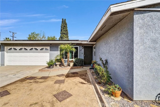 doorway to property featuring driveway, an attached garage, and stucco siding