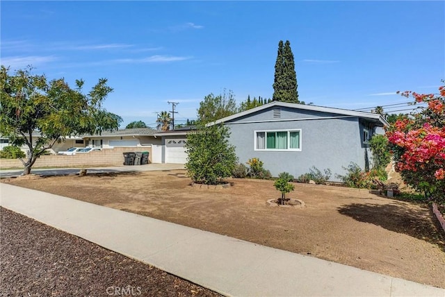 single story home featuring a garage, driveway, and stucco siding