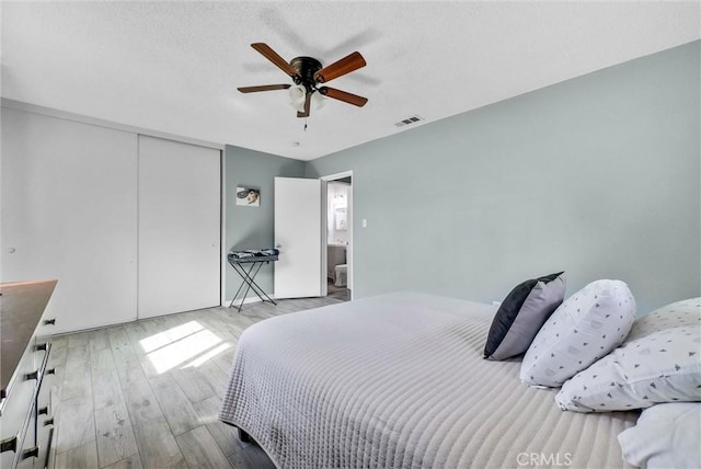 bedroom featuring a ceiling fan, a closet, visible vents, and light wood finished floors