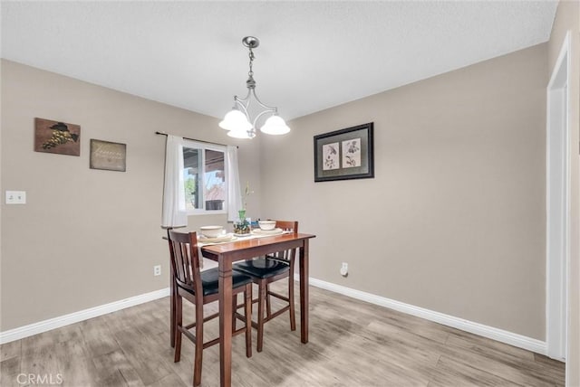 dining area featuring a chandelier, light wood-style flooring, and baseboards