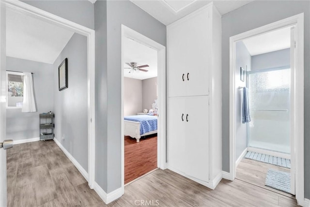 hall featuring light wood-style floors and baseboards