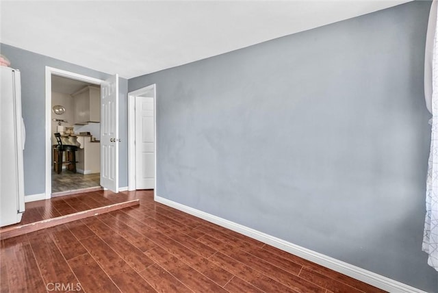 unfurnished room with dark wood-style floors and baseboards