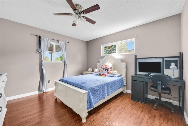 bedroom with multiple windows, baseboards, and wood finished floors