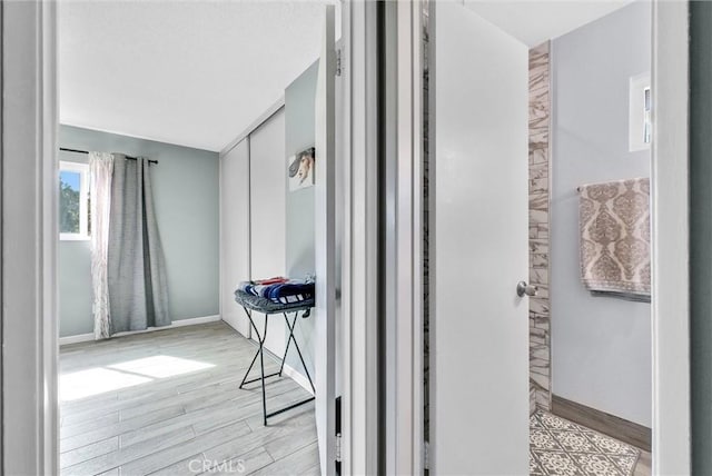 hall featuring light wood-type flooring and baseboards