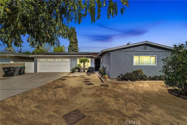 view of front of property with an attached garage, solar panels, concrete driveway, and stucco siding