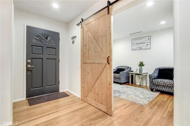 entrance foyer featuring a barn door, baseboards, wood finished floors, and recessed lighting