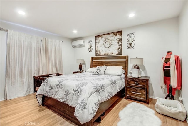 bedroom with an AC wall unit, light wood-type flooring, and recessed lighting