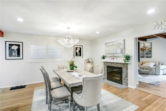 dining room featuring light wood-style flooring, a fireplace, baseboards, and recessed lighting