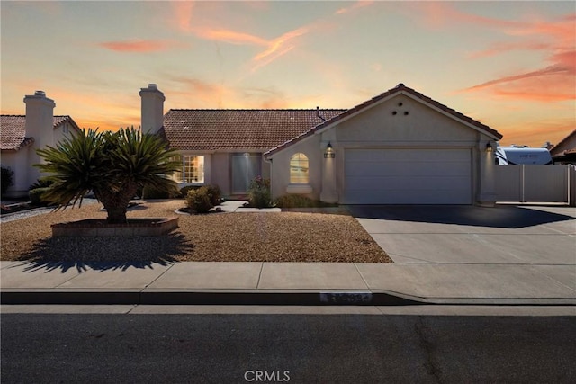 view of front of house with a garage, a tiled roof, concrete driveway, and stucco siding