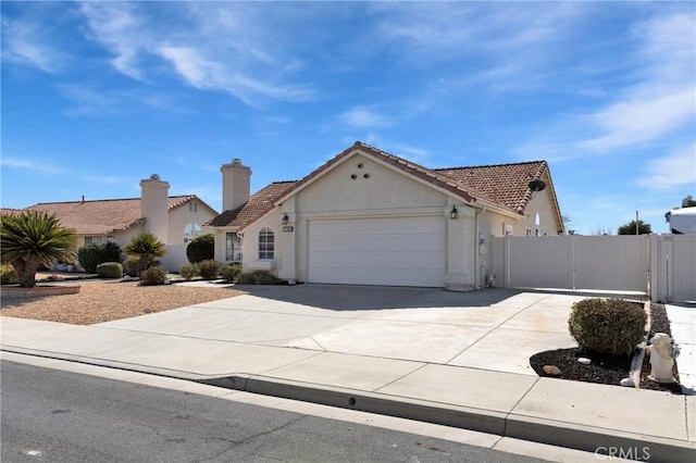 view of front facade featuring an attached garage, a gate, concrete driveway, and stucco siding