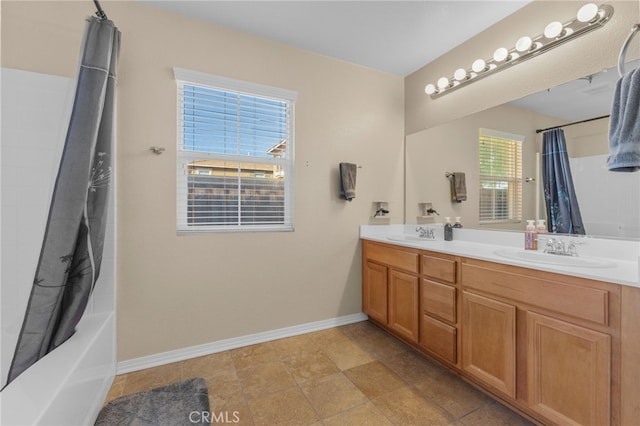 bathroom with shower / tub combo, a sink, baseboards, and double vanity