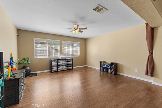 interior space with baseboards, ceiling fan, visible vents, and wood finished floors