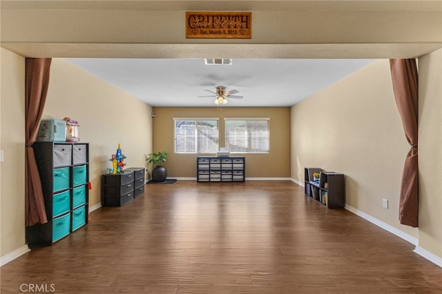 interior space with visible vents, dark wood-style flooring, a ceiling fan, and baseboards