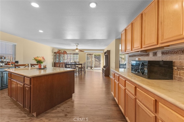 kitchen featuring dark wood finished floors, recessed lighting, light countertops, a kitchen island, and black microwave