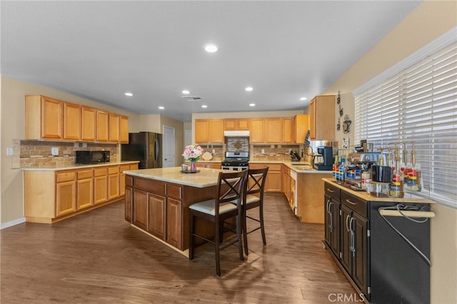 kitchen featuring tasteful backsplash, dark wood-style floors, a kitchen island, a kitchen breakfast bar, and black appliances