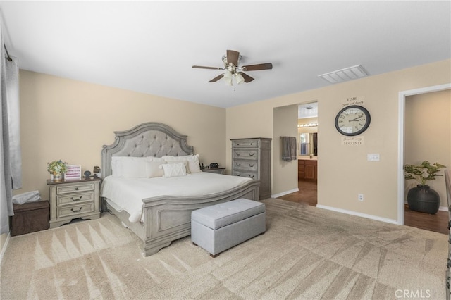 carpeted bedroom featuring a ceiling fan, ensuite bath, visible vents, and baseboards