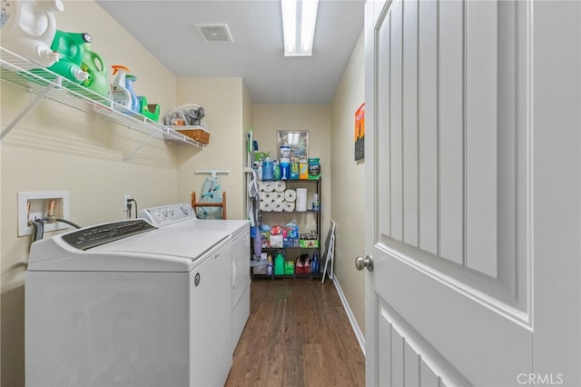 clothes washing area with dark wood-style floors, laundry area, visible vents, and washer and clothes dryer