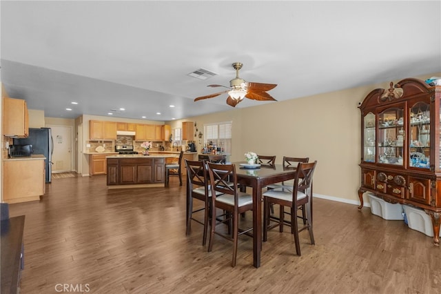 dining room with dark wood-style floors, baseboards, visible vents, and a ceiling fan