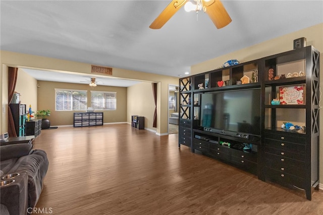 living room featuring ceiling fan, baseboards, and wood finished floors