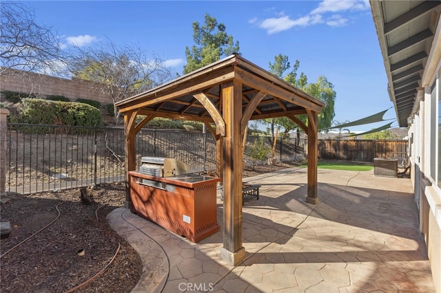 view of patio / terrace featuring a gazebo, a fenced backyard, an outdoor kitchen, and grilling area