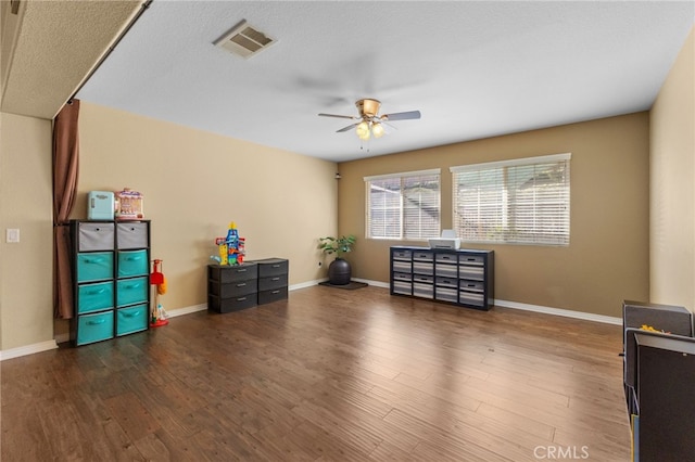 misc room with dark wood-style floors, ceiling fan, visible vents, and baseboards