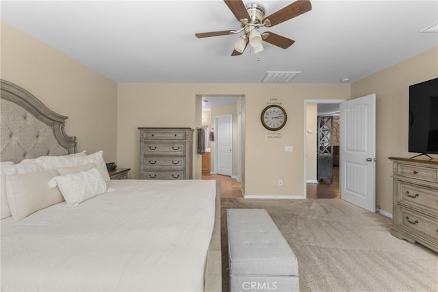 bedroom with visible vents, baseboards, light colored carpet, ensuite bath, and ceiling fan