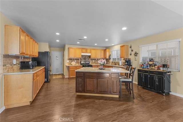 kitchen with dark wood-style floors, a breakfast bar, a kitchen island, and appliances with stainless steel finishes