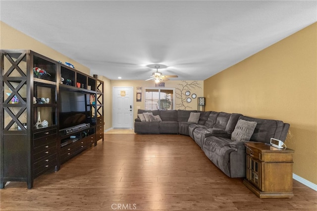 living room with ceiling fan, baseboards, and dark wood finished floors