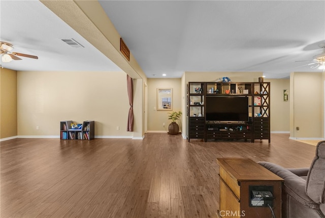 living room featuring baseboards, visible vents, a ceiling fan, and wood finished floors