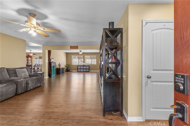 living room with a ceiling fan, baseboards, and wood finished floors